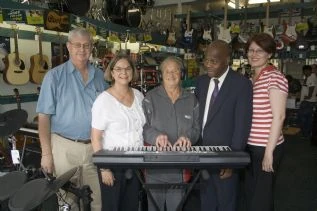 Brian Kreusch and Alette Bosch demonstrating the features of the Yamaha keyboard to an excited Tanie Minnie whilst Zelda Downey looks on